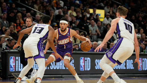 Feb 13, 2024; Phoenix, Arizona, USA; Phoenix Suns guard Devin Booker (1) drives between Sacramento Kings forward Keegan Murray (13) and forward Domantas Sabonis (10) in the first half at Footprint Center. Mandatory Credit: Rick Scuteri-USA TODAY Sports  